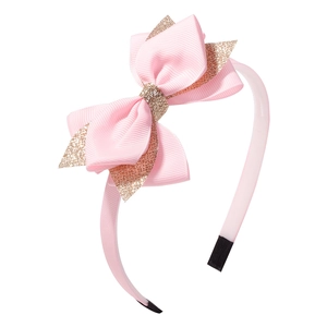 Détail de serre-tête rose à paillettes avec nœud en ruban gros-grain et embouts protégés