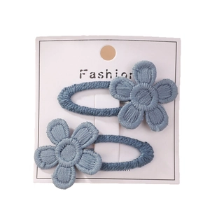 Set van twee blauw geborduurde madeliefje haarspeldjes op een witte fashion display kaart
