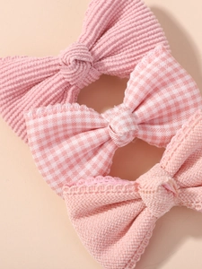 Dettaglio di fermagli per capelli rosa con velluto a coste, tessuto a quadri e pizzo