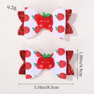 Detailed view of handmade bow hair clips with red apple print and glitter textures