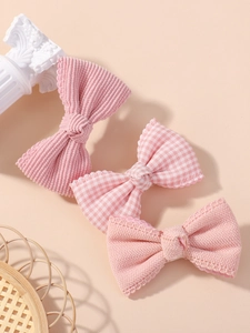 Dettaglio di tre fermagli rosa per capelli in velluto, tessuto a quadri e cotone