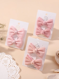 Dettaglio di fermagli per capelli in cotone biologico rosa a quadretti su carta