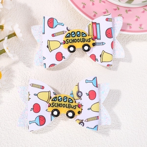 Close-up of fabric school bus hair clips with pencil prints and glitter accents