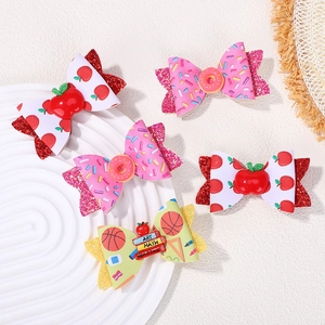 Detail of five-piece glitter bow hair clips featuring donut and apple motifs for girls