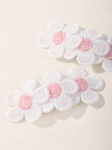 Macro shot of embroidered daisy hair clips with white petals and pink center details