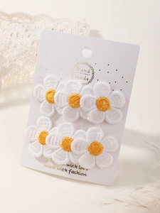 Detailed embroidery of white daisy hair clips with yellow centers on a handmade card display