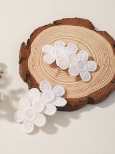 Detailed embroidery craft on white floral fabric hair clips set with layered petals