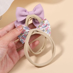Detail von Baby-Schleifen-Stirnbändern mit Blumenmuster aus weichem Cord in der Hand gehalten