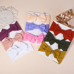 Set of 8 colorful baby bow headbands on white card, featuring soft nylon stretchy fabric