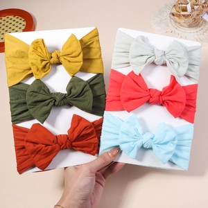 Detail showing set of six colorful ribbed nylon baby headbands with large soft bows