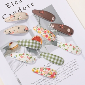 Détails de barrettes en tissu avec motifs floraux et coutures festonnées sur les bords