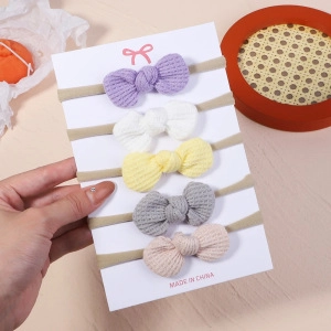 Close-up of five waffle knit baby headbands with knotted bows on a display card