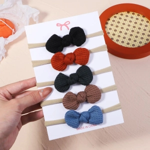 Close-up of five waffle knit bow headbands in black, brown, grey, blue, and tan shades