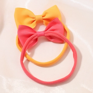 Detail of soft nylon infant headbands with ribbed grosgrain bow knots in orange and pink