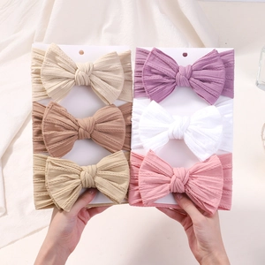 Gros plan d'un lot de 6 bandeaux bébé avec nœuds en nylon doux sur présentoirs