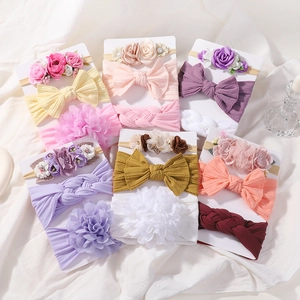 Vue détaillée de bandeaux bébé en nylon élastique avec fleurs en tissu et nœuds