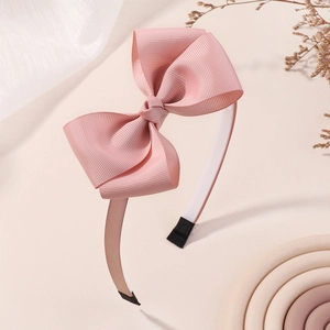 Vue détaillée du serre-tête pour enfants avec nœud en gros-grain rose et embouts protecteurs