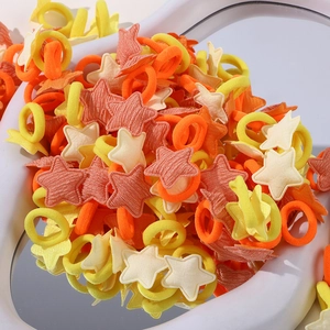 Gros plan d'élastiques à cheveux en tissu étoilé jaune et orange sur un socle blanc