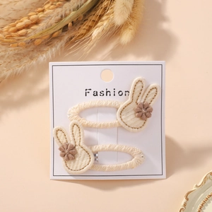 Detail of two handmade bunny hair clips with golden edges on a white display card