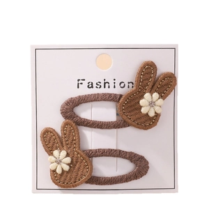 Pair of brown embroidered rabbit hair clips with white floral detail on a fashion card