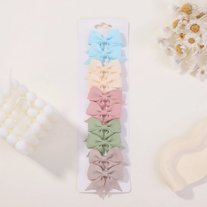 Detailed view of ten ribbon bow hair clips in pastel colors on display card