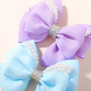 Close-up of bow hair clips with ribbed ribbons, white faux pearls and silver sequins