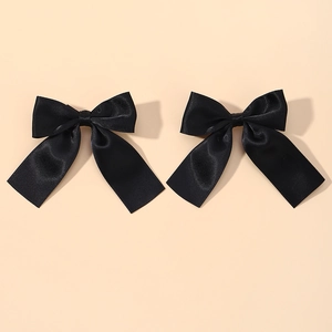 Close-up of a pair of black satin hair clips with long ribbons in a sweet bow design