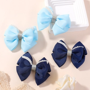 Close-up of handmade bow hair clips featuring grosgrain ribbon and pearl edge details