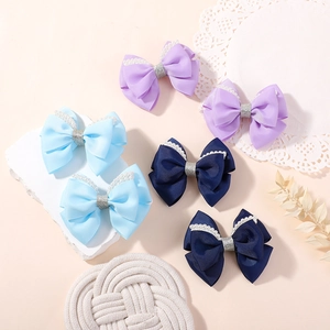 Detail view of handmade bow hair clips with faux pearls and glitter in six colors