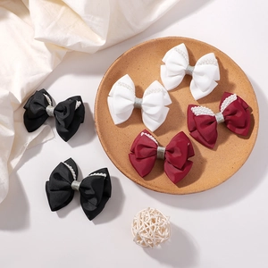 Detail of glitter ribbon hair bows with pearls in black, white and burgundy colors