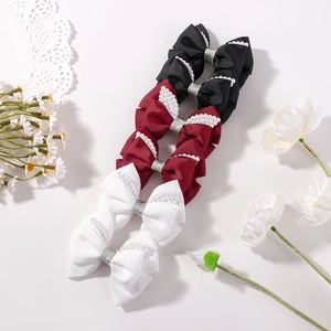 Detail of bow hair clips with white faux pearls in black, burgundy and white colors