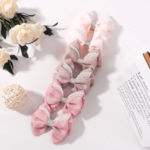 Macro detail of handmade glitter bow hair clips with faux pearl trim and grosgrain texture