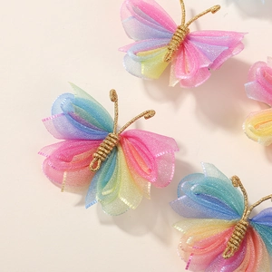 Détail macro d'un accessoire papillon en organza dégradé arc-en-ciel avec corps doré