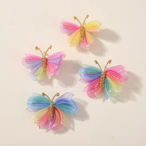 Détail de quatre barrettes papillon en tulle coloré avec dégradé et accents dorés