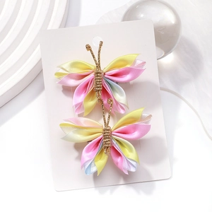 Détail de barrettes papillon en tulle dégradé avec accents en fil d'or sur présentoir