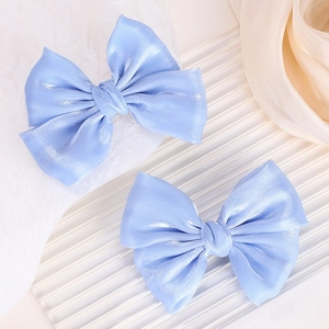 Detalle de pinzas para el cabello con lazo azul claro y textura de satén de seda