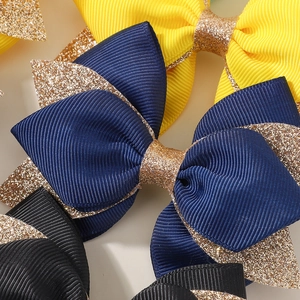 Detailed close-up of handmade glitter bow hair clips in navy, yellow, and black ribbon