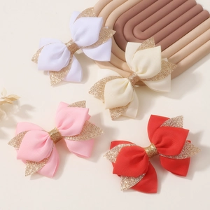 Detailed view of four handmade glitter bow hair clips in red, pink, cream, and white