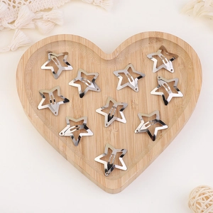 Detailed view of ten silver star hair clips arranged in a rustic heart shaped wooden tray