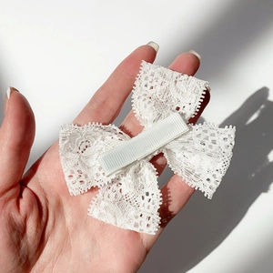 Nahaufnahme einer zarten weißen Spitzen-Haarschleife mit Krokodilklemme für Mädchen