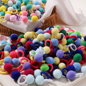 Close-up of vibrant fuzzy pom pom hair ties in a decorative basket and tray