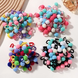 Close-up of assorted colorful plush ball hair ties set arranged on a minimalist surface