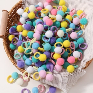 Close-up of colorful plush pom pom hair ties set in a basket with soft textures