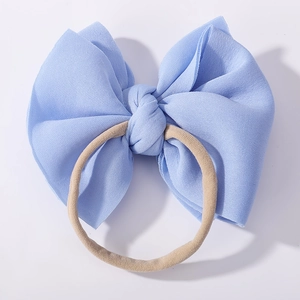 Detail of soft blue fabric bow headband with seamless nude nylon elastic band for babies
