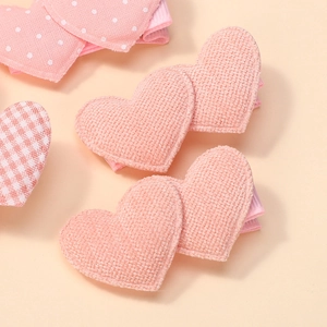Makroaufnahme von rosa Stoff-Haarspangen mit Herzform und Punkten für kleine Mädchen