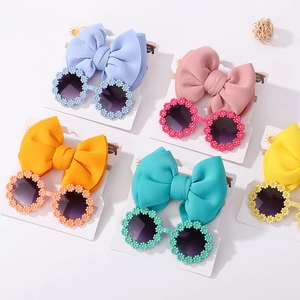 Flat lay of colorful daisy sunglasses and bow headband sets for baby girls
