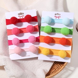 Détail de 8 bandeaux élastiques pour bébés avec pompons doux sur carte support