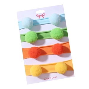 Lot de quatre bandeaux en nylon colorés avec pompons en peluche sur carte de vente