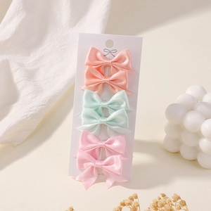 Detailed set of six mini silk satin bow hair clips in pastel colors on a display card