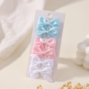 Detailed view of a 6-piece set of mini solid color bow hair clips on a display card